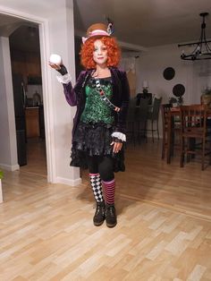 a woman with red hair is dressed up as a mad hatter and holding a white ball