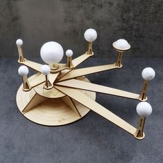 a sculpture made out of wood and white balls on it's sides, sitting on top of a gray surface