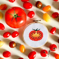 a tomato and some tomatoes on a white surface with the cross stitch pattern in it