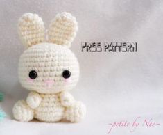 a small crocheted bunny sitting next to a flower on a white background with the words free pattern written below it