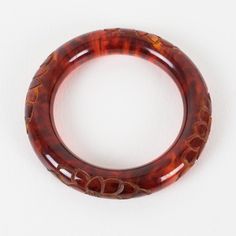 This is part of Chairish’s Costume Jewelry assortment.  Stunning red tea amber marble Bakelite bracelet bangle. Chunky rounded domed shape with a deep floral carving all around. Intense orange-red color with lots of cloudy swirling and translucency. Measurements: Inside across is 2.50 in diameter (6.4 cm) - outside across is 3.63 in diameter (9.2 cm) - width is 0.57 in wide (1.4 cm) - the wall is 0.57 in thick (1.4 cm).  Please see the measurements noted above in the description for the best app Carved Round Bangle For Formal Events, Carved Round Bangle For Formal Occasions, Elegant Bakelite Bracelets As A Gift, Carved Formal Bangle, Elegant Amber Bangle Bracelet, Luxury Red Bangle, Formal Brown Round Bangle, Elegant Handmade Red Bangle, Elegant Bakelite Bracelets For Gift