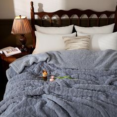 an unmade bed with two candles on it and a blue comforter in the foreground