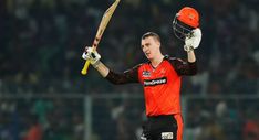 a cricket player holding his bat and helmet in the air while standing on a field