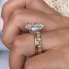 a woman's hand holding an engagement ring with two stones on the band and a diamond