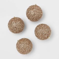 three gold glittered round ornaments on a white surface