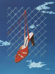 a pair of red high heeled shoes hanging from a chain link fence with clouds in the background