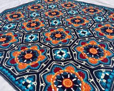 a crocheted blue and orange rug on top of a bed