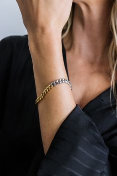 Featuring a striking blend of gold and silver, the mixed metal cuban link chain bracelet creates a bold and contemporary look. Its durable construction and eye-catching design make it the perfect statement piece to elevate any outfit.- Stainless steel base - Length: 7" / 177.8mm (one size fits most) - Width: 0.24" / 6mm- Lobster clasp- Available in mixed-metal- Engraved with signature MC branding- Hypoallergenic, non-tarnish, water-resistant Modern Chunky Chain Cuban Link Bracelets, Modern Bracelets With Chunky Cuban Link Chain, Modern Chunky Cuban Link Chain Bracelet, Modern Cuban Link Chain Bracelet With Solid Construction, Modern Chunky Chain Cuban Link Bracelet, Modern Cuban Link Curb Chain Bracelet, Modern Curb Chain Link Bracelet, Modern Cuban Link Bracelet With Chunky Chain, Modern Chunky Cuban Link Bracelet