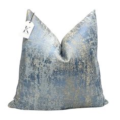 a blue and gold pillow with a tag on it