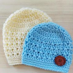 two crocheted hats sitting on top of a wooden table next to each other