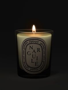 a candle that is lit up in the dark with an orange and black label on it