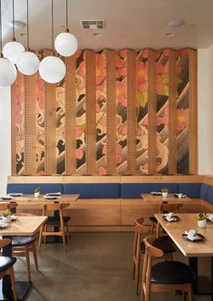 an empty restaurant with wooden booths and blue seats, artwork on the wall behind them