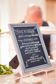 a chalkboard sign with writing on it in front of a table full of food