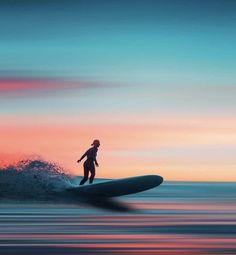 a man riding a surfboard on top of a wave in the ocean at sunset