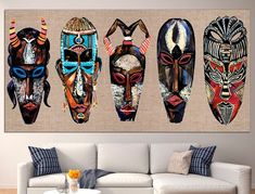 three african masks hanging on the wall above a white couch in front of a coffee table