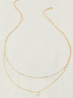 This delicate two-layer necklace features a dainty chain adorned with colorful painted dots, adding a playful touch to any ensemble. The second layer boasts a classic gold chain with a timeless pearl charm, creating an elegant and sophisticated contrast. Gold Delicate Chain Layered Necklace With Pearls, White Double Strand Layered Necklace, White Double Strand Layered Necklace With Delicate Chain, White Double Strand Pearl Chain Layered Necklace, Dainty Double Strand Pearl Chain Layered Necklace, Dainty Pearl Chain Layered Necklace, Dainty Gold Layered Pearl Necklace, Dainty White Layered Pearl Chain Necklace, Gold Layered Necklace With Pearl Pendant