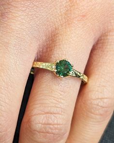 a close up of a person's hand with a green ring on their finger