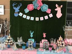 a table topped with cake and cupcakes next to a green wall covered in decorations