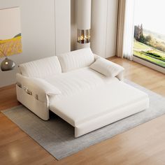 a white couch sitting on top of a hard wood floor next to a large window