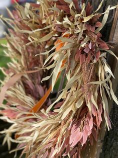 dried flowers are hanging on the side of a wooden door frame in front of a tree