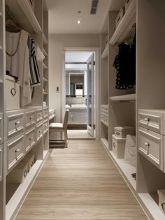 an empty walk - in closet with white drawers and wooden flooring is seen here