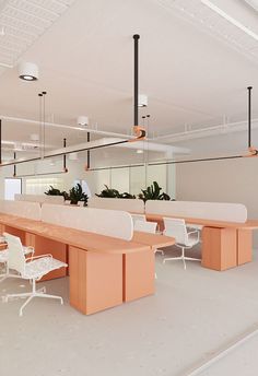 an empty conference room with white chairs and orange tables in the center, along with plant life on the walls