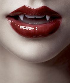 a woman's lips with white teeth and blood on the lip is painted red