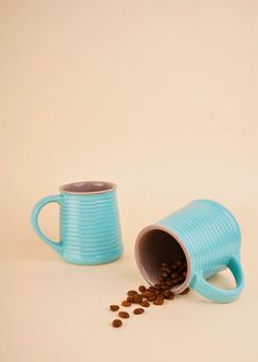 a blue coffee mug next to a pile of coffee beans