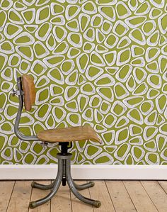 a chair sitting in front of a wall with a green and white pattern on it