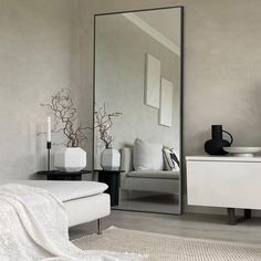 a white bed sitting next to a tall mirror