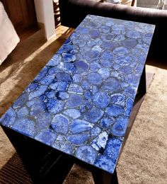 a blue table sitting on top of a carpeted floor in a living room next to a couch