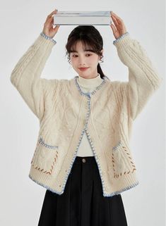 a young woman is holding her head in the air while wearing a white cardigan