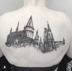 a woman's back tattoo with hogwarts castle on it