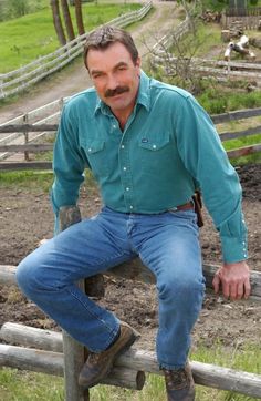 a man sitting on top of a wooden fence