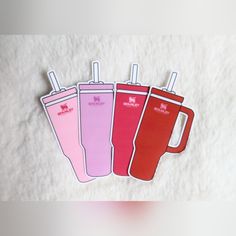 three pink and one red cups with straws in them sitting on a white surface