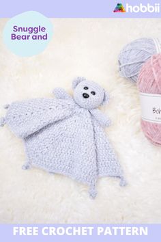 two balls of yarn and a crocheted teddy bear are on a white blanket