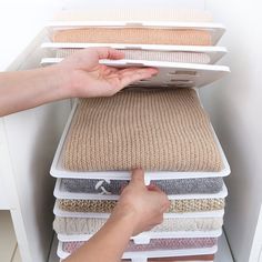 a person reaching for the top of a stack of rugs