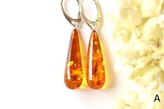 The earrings of Baltic amber in rich honey colour will not betray your expectations. It is one of the most popular colours of Baltic amber. Executed in the shape of a drop, they will perfectly match to any outfit. These lightweight, elegant, sophistically sparkling earrings with a spangle inside are an irresistible piece of jewellery that you will love wearing every day. It is a genuine, natural and unique piece of jewellery created by nature, so you will feel special on every occasion. Delight Cheap Amber Dangle Jewelry, Cheap Artistic Orange Jewelry, Luxury Amber Earrings For Anniversary, Luxury Amber Earrings For Formal Occasions, Affordable Orange Hypoallergenic Earrings, Cheap Amber Drop Earrings, Cheap Unique Orange Earrings, Cheap Amber Dangle Earrings, Cheap Orange Drop Earrings