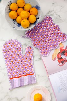 a bowl of oranges sitting on top of a table next to an open book