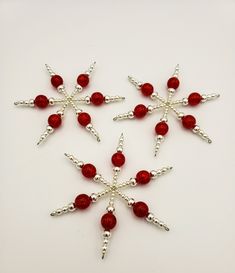 six red beaded snowflakes on a white surface with silver beads in the middle