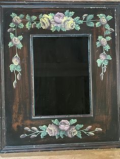 an old wooden frame with flowers painted on it's sides and leaves around the edges