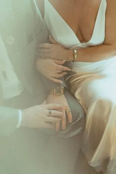 a man and woman sitting next to each other in front of a white wall with sunlight coming through the window