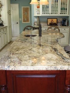 a large kitchen with marble counter tops and white cabinets