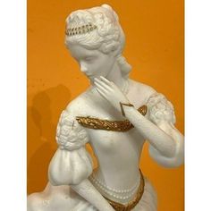 a statue of a woman in white with gold trimmings on her head and hands clasped to her chest