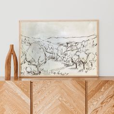 an abstract painting is displayed on a wooden cabinet next to a vase and wood sculpture