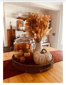 a glass jar filled with pumpkins and gourds on top of a wooden table