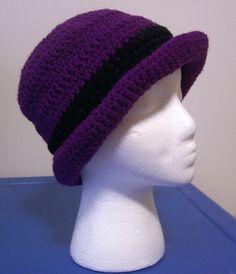 a white mannequin head wearing a purple and black crochet knitted hat