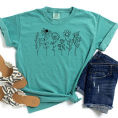 This slightly minimalist Wildflowers graphic tee is perfect for your spring and summer wardrobe.  Are you looking for your new favorite t-shirt? Our graphic tees are custom created specifically for you and made by me not sourced out to a print shop. Select your shirt style, color, and print design. Your item will be created using direct-to-garment (DTG) print technology. Large garment printers utilize digital images to create unique and colorful designs. Water-based inks will be infused into the Trendy Spring Tops With Plant Print, Trendy Plant Print Tops For Spring, Trendy Tops With Plant Print For Spring, Spring Relaxed Fit T-shirt With Plant Print, Spring Relaxed Fit Plant Print T-shirt, Spring Graphic Tee With Screen Print, Spring Graphic Tee Shirt With Screen Print, Spring Green T-shirt With Floral Embroidery, Spring Plants Print Short Sleeve T-shirt