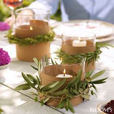 candles are sitting on the table with greenery around them