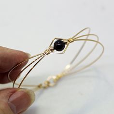 A sweet design of three strands of 14kt gold filled wire featuring a single 6mm genuine garnet bead flanked by two small 14kt gold filled beads. The garnet bead is a very deep dark red, almost black (unless you hold it up to the light or next to something that's actually black!) This stylish, well-fitting bangle will go with most everything in your closet, and is sure to get noticed every time you wear it. So delicate and feminine! The sturdy built-in hook and eye clasp is easy to get on and off Adjustable Gold Gemstone Jewelry, Gold Hand Wrapped Beaded Bangle Bracelets, Hand Wrapped Gold Beaded Bangle, Gold Spiritual Hand Wrapped Bracelets, Spiritual Hand Wrapped Gold Bracelets, Spiritual Hand-wrapped Gold Bracelets, Gold Wire Wrapped Bracelets With Round Beads, Gold Wire Wrapped Metal Bracelets, Gold Hand-wrapped Bracelets For Gifts